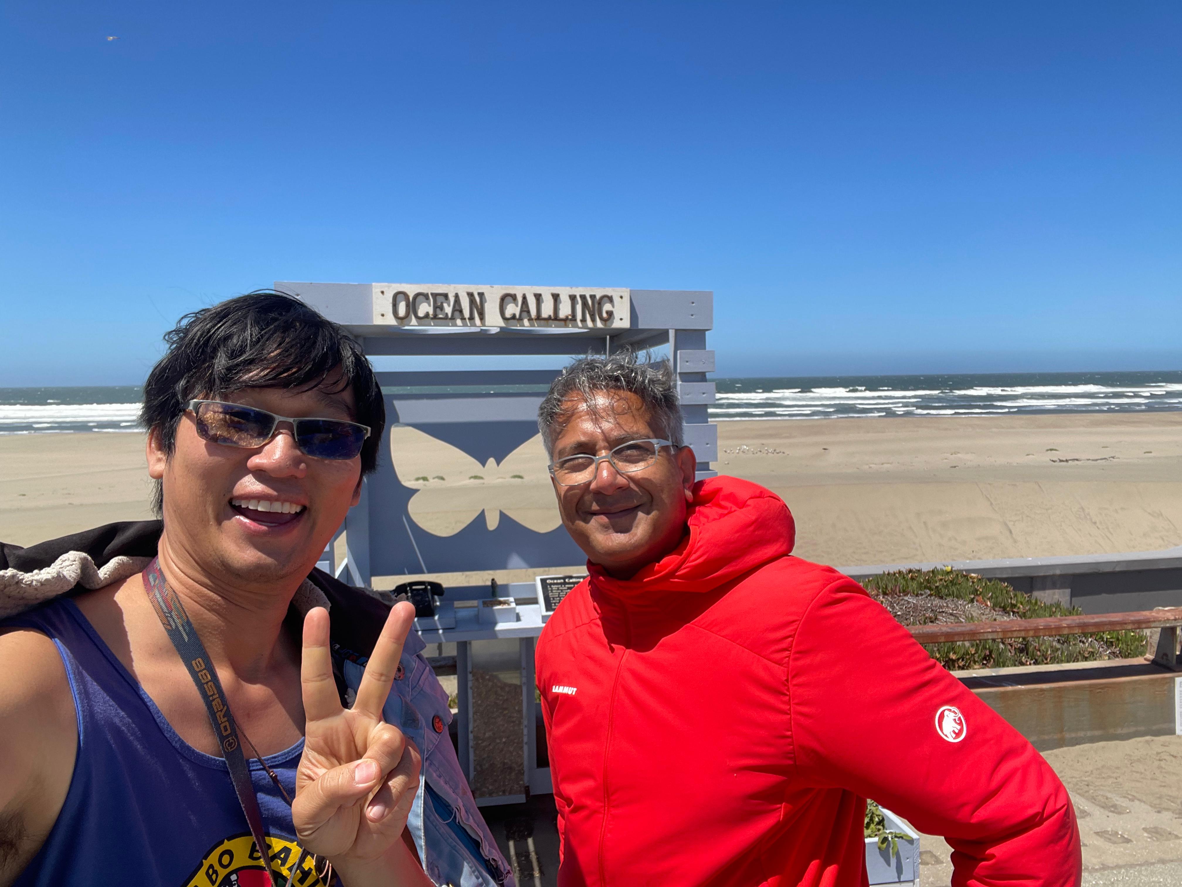 Two figures walking along Ocean Beach — Gary and his old colleague Bilal, mid-stroll